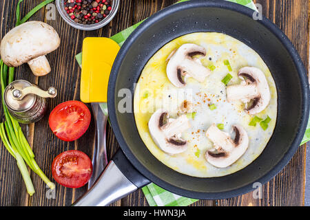 Fried eggs with mushrooms in frying pan Stock Photo