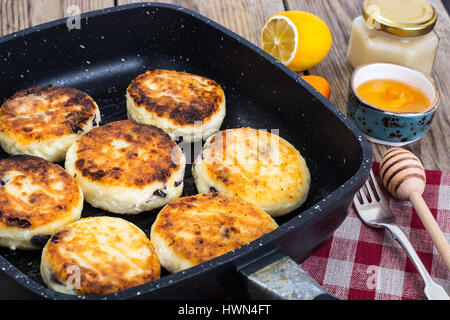 Cheesecakes with raisins in frying pan Stock Photo