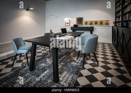 A contemporary table - made out of charred wood according the shou-sugi-ban technique - in a library. Architecture and interior design. Stock Photo