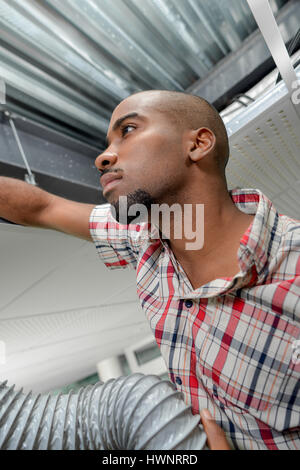 Man in roofspace with ventilation hose Stock Photo