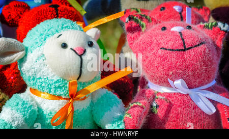 The souvenirs in the form of amusing dolls sewed from rags of fabric and laces. Are presented on a beautiful background with an embroidery. Stock Photo