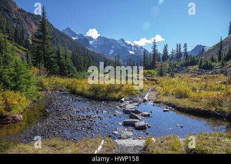 Shallow stream with stepping stones lies across the popular Lake Ann hiking trail near Mount Baker, WA Stock Photo