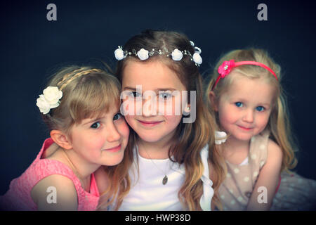 Portrait of sisters blonde girls, children kids hugging on first holy communion day Stock Photo