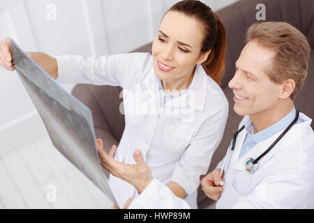 You did a great job. Two prominent friendly medical workers finding consensus on the diagnosis and discussing treatment while looking at patients MRI  Stock Photo