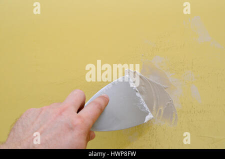 Hand with putty knife repair damaged wall Stock Photo