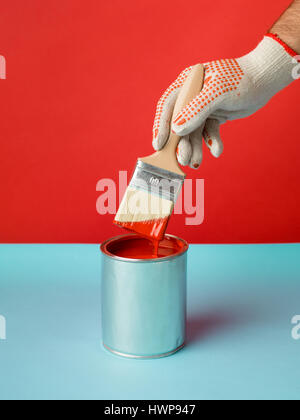minimal image freshly painted red background and can with brush in hand on blue table Stock Photo