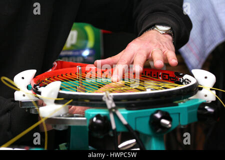 Melbourne, Australia - October 17, 2009: Racquet stringer weaving cross strings of synthetic gut string in a Tennis racquet on a electronic tournament Stock Photo