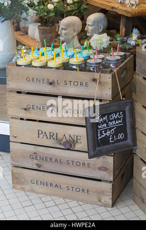 Cirencester - Jam jars with straws for sale in wooden crates outside shop at Cirencester, Gloucestershire in March Stock Photo