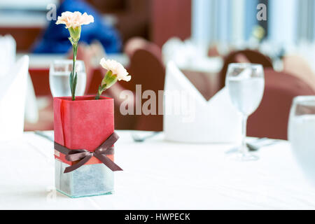 close up decorate red vase with glass and flower on dinner table Stock Photo