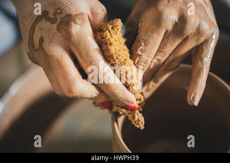 Cropped image of female potter scrubbing clay pot at workshop Stock Photo