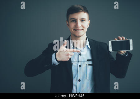 Businessman pointing finger on blank smartphone screen over black background Stock Photo