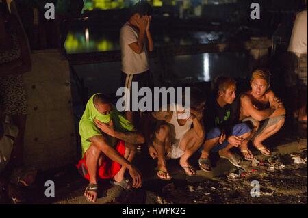 October 5, 2016 - Manila, National Capital Region, Philippines - Locals gather near the scene where drug suspect Benjamin Visda was shot dead by plain clothed police on a muddy unpaved road around100m from Tondo Police Station 1. Eyewitnesses who refused to be identified claimed that Visda pleaded for his life before being shot in the back of the head. The claimed that the policemen then removed his handcuffs, which were locked behind his back and put them on with his hands in front of his body. (Credit Image: © Dave Tacon via ZUMA Wire) Stock Photo