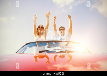 Crazy couple standing in red cabriolet on a sunny day Stock Photo