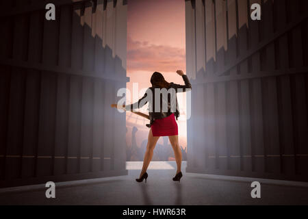 Brunette in biker jacket playing guitar against football stadium with cheering crowd 3d Stock Photo