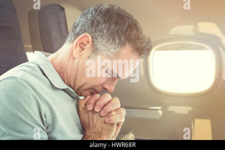 Tensed man standing against window  against empty seat in modern plane Stock Photo