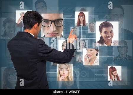Thoughtful asian businessman pointing against dark blue background Stock Photo