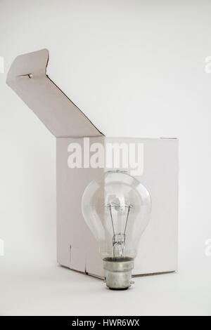 Plain white box with lid open and light bulb in front. Isolated on white background leaving copy space for text. Stock Photo