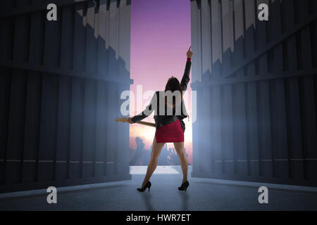 Brunette in biker jacket playing guitar against football stadium with cheering crowd 3d Stock Photo