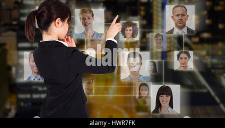 Thoughtful businesswoman pointing against glowing road amidst building in city at night Stock Photo