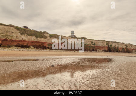 HUNSTANTON, ENGLAND - MARCH 10: Old Hunstanton Lighthouse (now a residence) reflected in puddle on beach. HDR image. In Hunstanton, Norfolk, England.  Stock Photo