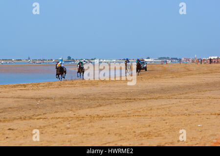 SANLUCAR DE BARRAMEDA, CADIZ, SPAIN - AUGUST 11: Unidentified riders race horses on Sanlucar de Barrameda beach on August 11, 2011 in Sanlucar de Barr Stock Photo