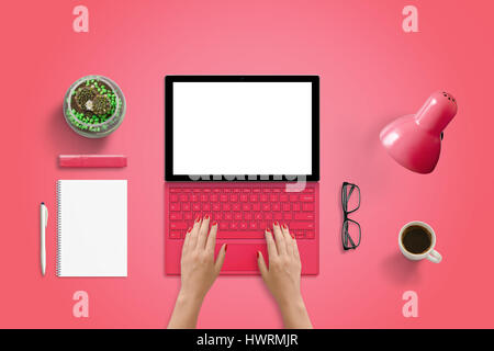 Red tablet with keyboard on red desk. Isolated screen for web site or app presentation. Top view scene. Pad, plant, glasses, coffee, lamp beside. Stock Photo