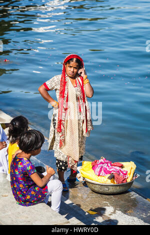 Local Indian woman doing her washing and children on the lakeside shore of Pichola Lake, Udaipur, Indian state of Rajasthan Stock Photo