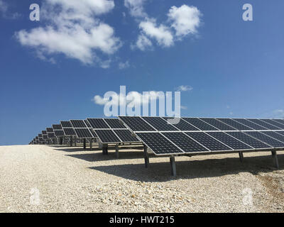 Solar panels on field against blue sky during sunny day Stock Photo