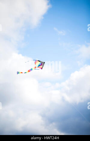 Low angle view of colorful kite flying in cloudy sky Stock Photo