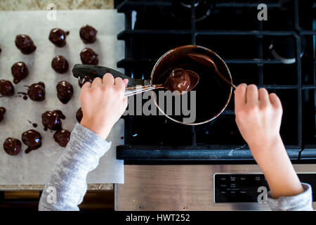 Cropped hands of girl making chocolate truffles in kitchen at home Stock Photo