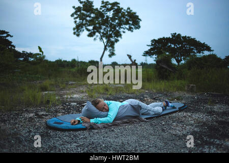 Woman sleeping on bag against sky Stock Photo