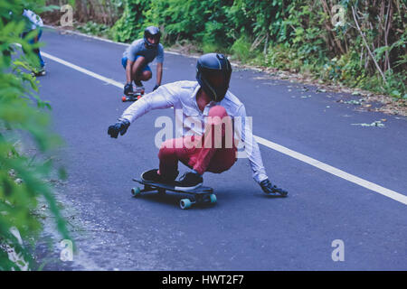 Male friends crouching while skateboarding on road Stock Photo