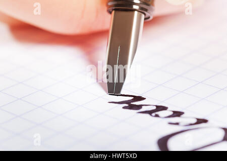Fountain pen writing the word Dear on graph pad Stock Photo
