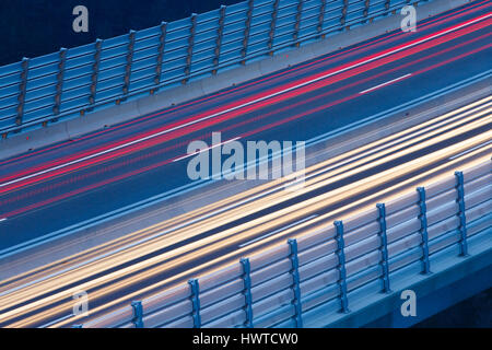 Blurred lights of vehicles driving on a tall viaduct in rush hour, long exposure. Transportation, on the road, connectivity and internet concept, back Stock Photo