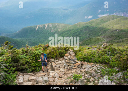 A determined young woman with trekking poles climbs up a steep, rocky section of Franconia Ridge on the New Hampshire section of the Appalachian Trail Stock Photo