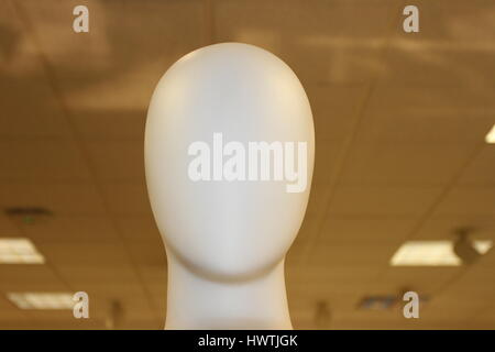 White plastic mannequin. Faceless person or dummy. Faceless mannequin with no clothes on the demonstration. A face of a plastic mannequin. Head dummy. Stock Photo