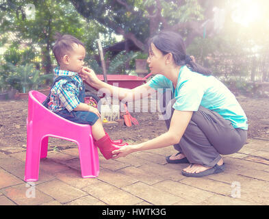 Mother wearing red color boots to baby and talking together  , Family scene mother and baby in  Thailand Stock Photo
