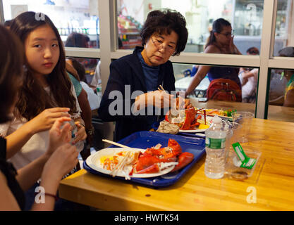 New York City, Usa - July 12, 2015: Asian tourists eating fresh lobsters in Chelsea Market. The market has a number of eateries and food outlets. Stock Photo