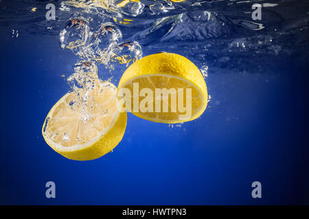 Fresh lemon dropped into water background Stock Photo