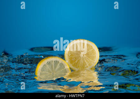 yellow lemon dropped into water background Stock Photo