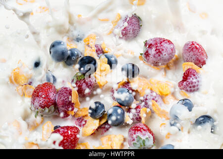 splash corn flakes with fresh berries and pouring milk background Stock Photo