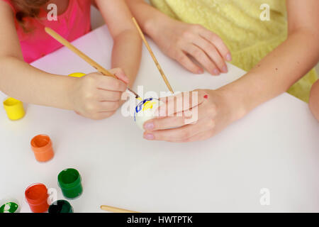 Happy easter A mother, and daughters painting Easter eggs. Happy family preparing for Easter. Stock Photo