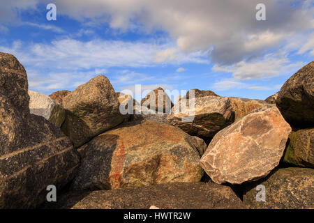 STAITHES, ENGLAND - MARCH 1: Pile of pink/orange rocks against blue sky and white clouds. In Staithes, North Yorkshire, England. On 1st March 2017. Stock Photo