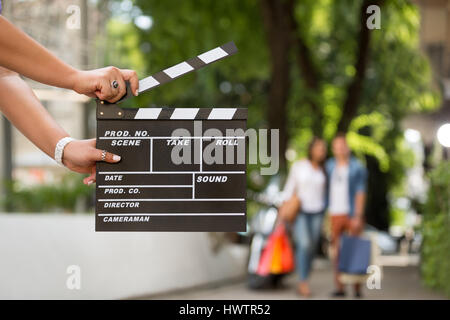 Female  holding clapper board with shopping couple in background, concept start sale Stock Photo