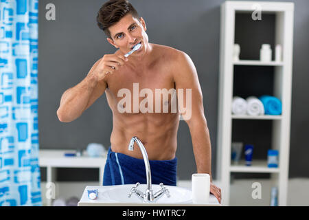 man brushing the teeth in the bathroom front of sink Stock Photo