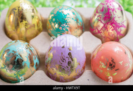 Foiled and Colorful Easter Eggs in Pink, Aqua, Yellow, Orange and Gold, in an egg container Stock Photo