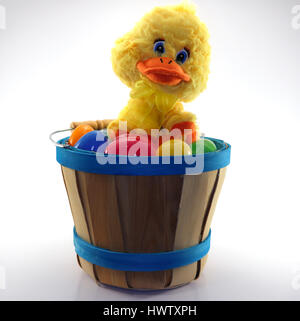 Cute duckling sitting on assorted easter eggs in a wooden bucket Stock Photo