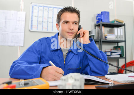 Electrician on the phone in his office Stock Photo