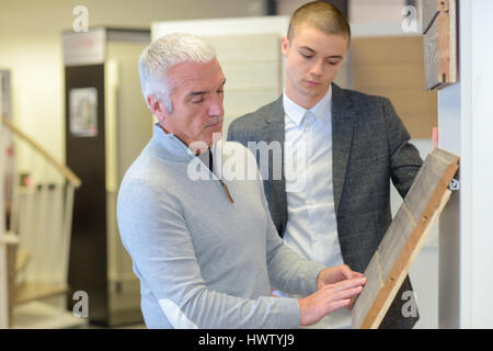 client choosing parquet flooring from different samples with sales representative Stock Photo