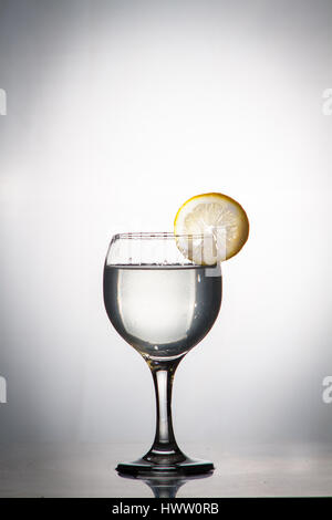Glass glass of water with lemon on the isolated background. Mountain mineral pure mountain water with gas bubbles and a lemon slice and spray tonic re Stock Photo